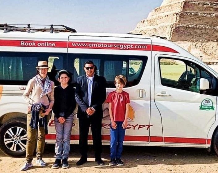 Various transportation options including tour buses, taxis, and private cars traveling toward the Giza pyramid complex