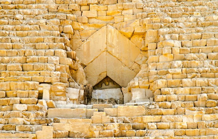 Main entrance gate to the Giza pyramid complex with ticket booth and visitor facilities surrounded by palm trees