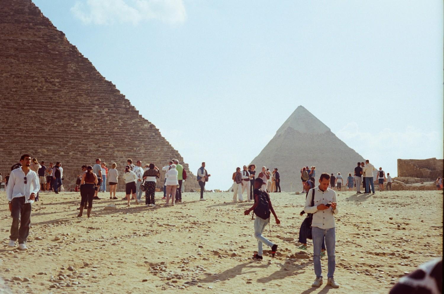 Large tourist group with professional guide standing in front of the Great Pyramid, showing typical group tour experience
