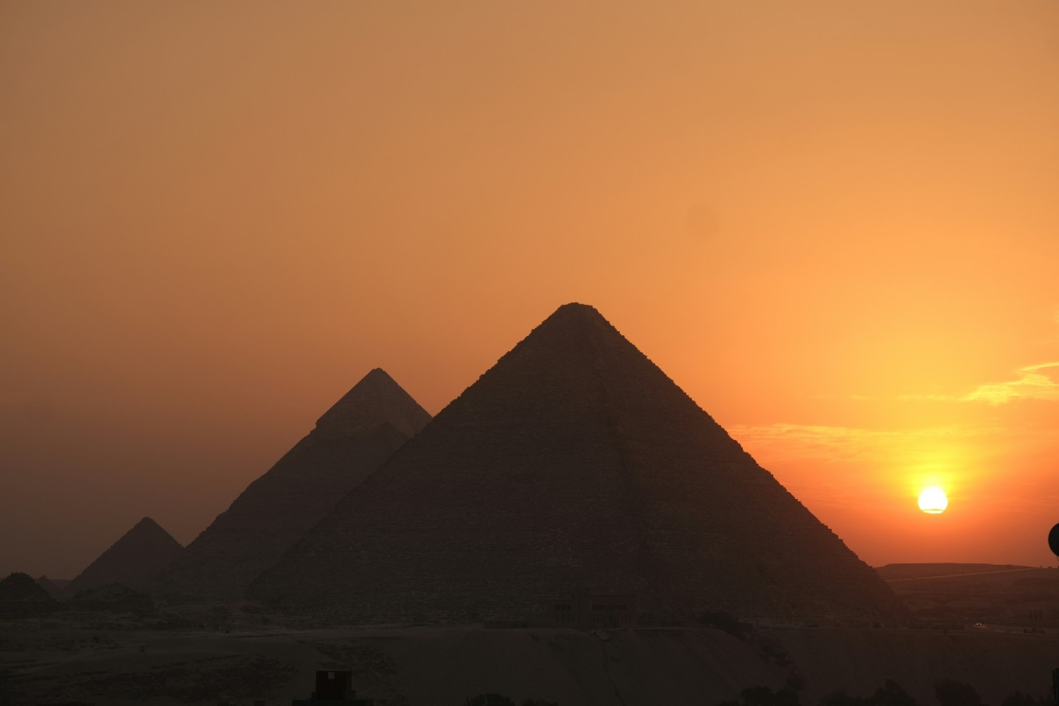 Panoramic view of the three main pyramids at Giza during golden hour sunset with dramatic sky and desert landscape