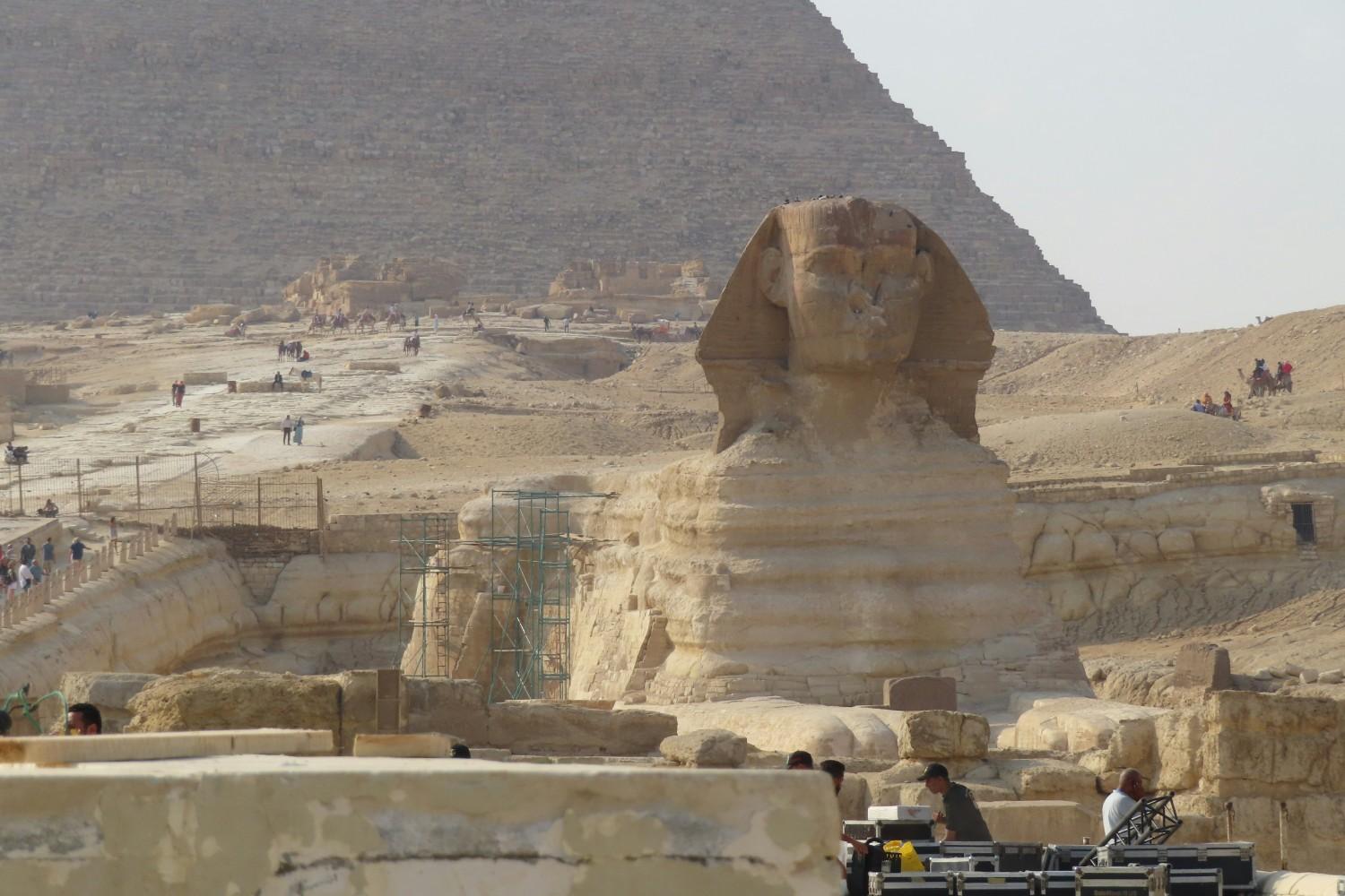 Close-up view of the Great Sphinx with the Great Pyramid of Khufu in the background, showing ancient limestone construction details